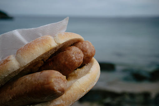 close up of a Breakfast Sausage bun at the coast in Newquay, Cornwall.