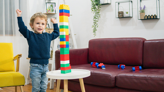 Child playing with colorful toy blocks. Little boy building tower at home or day care. Educational toys for young children. Construction block for baby or toddler kid.