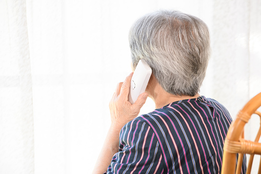 Rear view of a senior woman anxiously talking on the phone