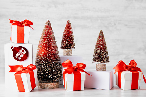 Bright Christmas Background with red and gold decorations with Christmas tree and gift boxes on white wooden table