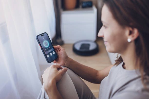 istock Woman using smart phone to control robot vacuum cleaner with an app 1779965583