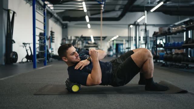 SLO MO Male Athlete in Sportswear Stretching Back Muscles on Foam Roller at Gym