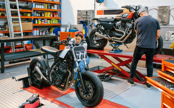 Mechanic couple repairing custom motorcycles on factory stock photo