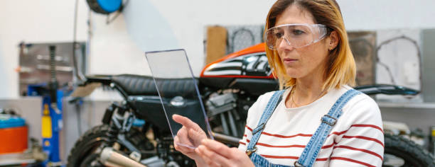 istock Female mechanic with security glasses holding transparent tablet 1779977689