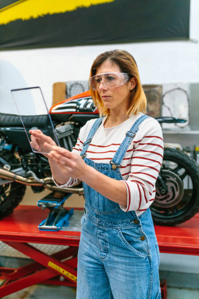 istock Female mechanic with security glasses touching transparent tablet 1779977691