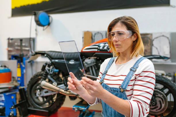 istock Female mechanic with security glasses holding transparent tablet 1779977692
