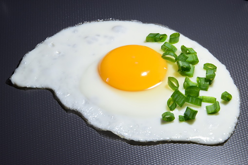 fried egg - white and yolk sprinkled with chives close-up isolated