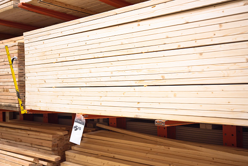 Stack of 2x4 10 feet long stud pine lumber with price tag at home improvement hardware store shelves uses for framing, houses, sheds, and other structures, timber construction. Industrial background