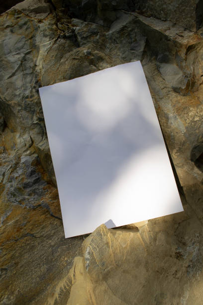 istock Mockup of white sheet with shadows on sand colored rocky background 1780021315