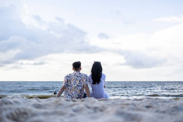 istock Couple on the beach watching the sea 1780026234