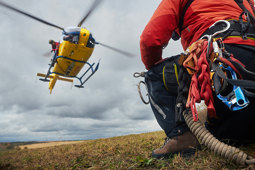 Selective focus on safety harness of paramedic of emergency service in front of landing helicopter. Themes rescue, teamwork and hope.