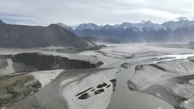 Scenic aerial view drone view flying over sand dunes Sarfaranga Cold Desert, Surrounding with Snow Cap Mountain in Skardu, Northern Pakistan