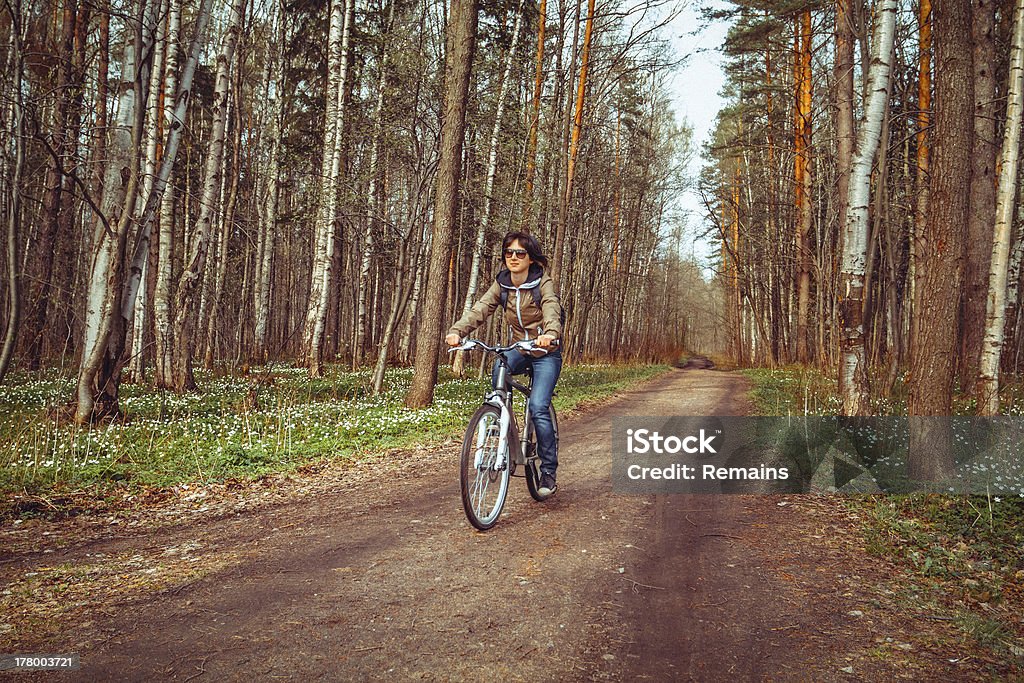 Mujer joven montando bicicleta en un bosque - Foto de stock de Actividad libre de derechos