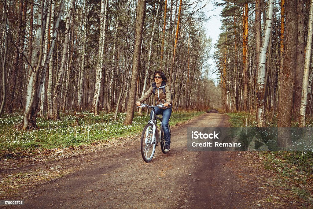 Giovane donna in bicicletta di equitazione in una foresta - Foto stock royalty-free di Adulto