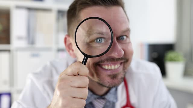 Smiling male doctor looks through magnifying glass 4k movie