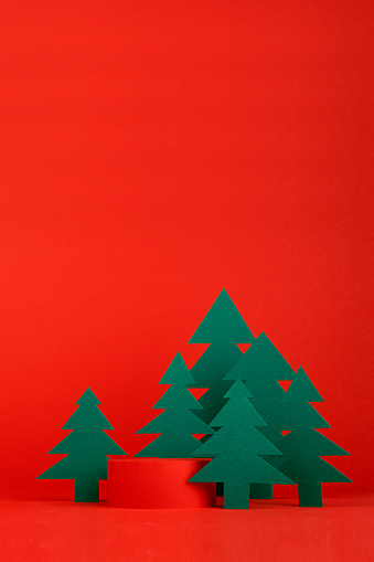 Christmas tradition background - red scene, cylinder podium mockup for presentation gifts, cosmetic products, good with green paper spruce forest, vertical. New year template for card, poster, flyer.