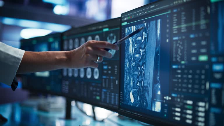 Modern Medical Research Center: Anonymous Doctor Pointing At Desktop Computer Monitor With CT Scan Of Human Spinal Cord. Specialist Looking For Tumors Or Damage, Looking For Treatment Methods.