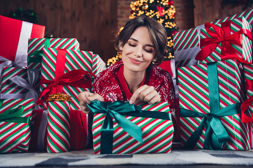 Photo of attractive young woman lying floor open gift pull ribbon dressed red sweater christmas room interior design tree decorated indoors.