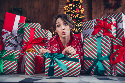 Photo of lovely young lady pull ribbon open gift impressed dressed stylish red sweater christmas tree decorated interior living room.