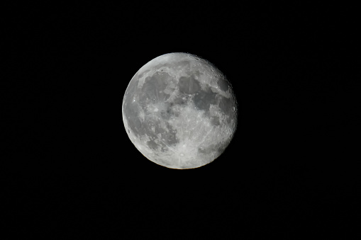 Stock photo showing a full moon shining against a black, night time, starless sky.