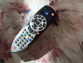 TV remote control on floral pattern sofa fabric with sunlight reflection