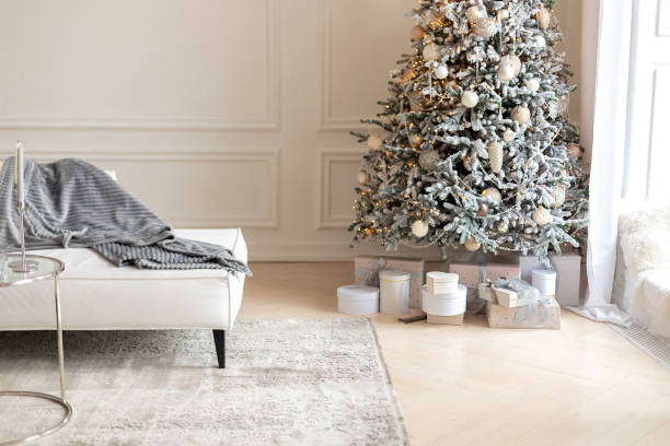 istock Modern interior living room with large light  white sofa and Xmas tree. Comfortable couch with three cushions and a blanket standing in bright room interior with grey carpet in a modern interior. 1780100796