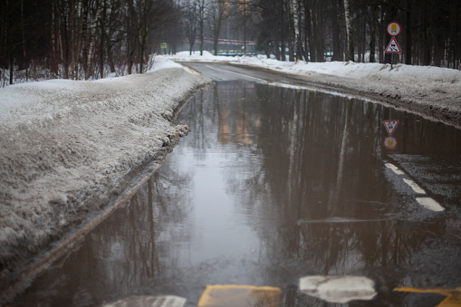 Snow is melting on the road. Puddle in spring. Highway in the water. Melting snow on the highway in the city. Wet Street.