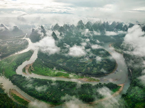 Aerial view of great Landscape from Damian mountain, Xingping Ancient Town covered by clouds in the morning. Sailboats among the Li Jiang river between the karst mountains in Yangshuo Country, Guilin, Guanxi Province, China