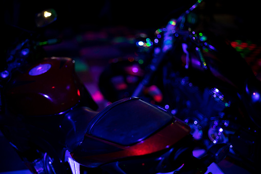 Motorcycle in dark. Transport in blue light. Bike at disco. Light on machine body.