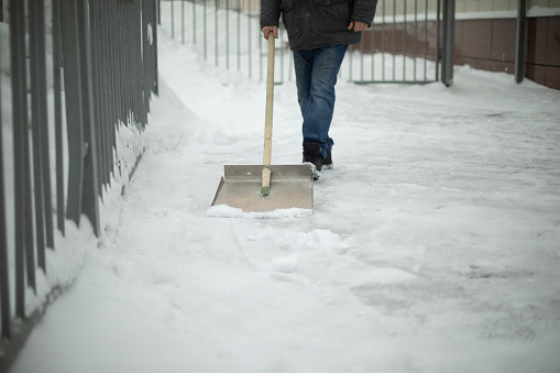 Snow removal on street. Shovel for track cleaning. Man cleans up yard. Large shovel.