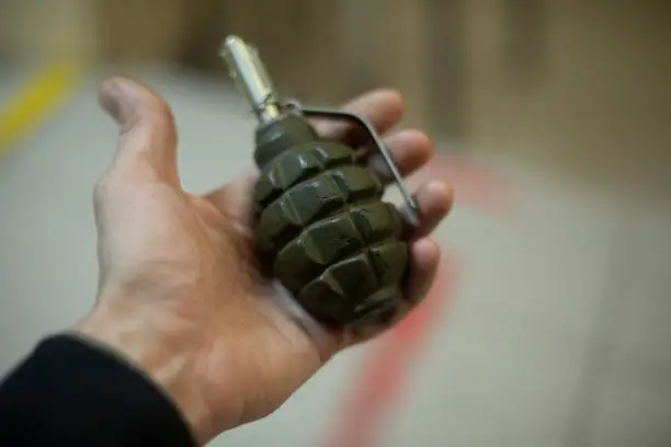 Hand holding grenade. There are explosives in palm of person's hand. Munitions. Training grenade.
