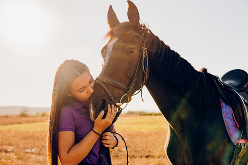Beautiful young woman enjoying with her brown arabian horse in the nature.