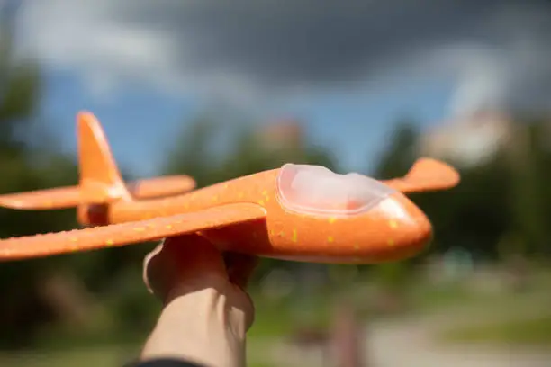 Photo of Plane in hand. Toy plane. Orange foam. Lightweight material.
