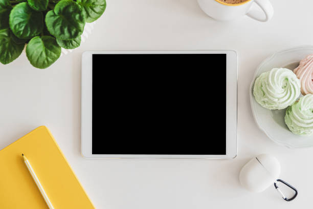 istock Mock-up digital tablet with empty screen, notebook, coffee cup, food and plant on white table. Top view. Flat lay 1780123480