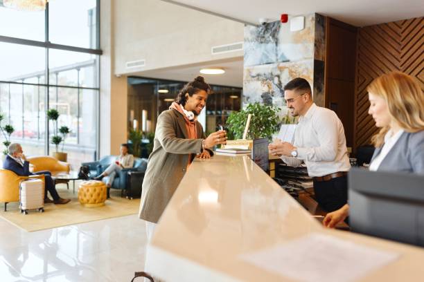 istock Casually dressed businessman using smartphone to check in at the hotel reception 1780139323