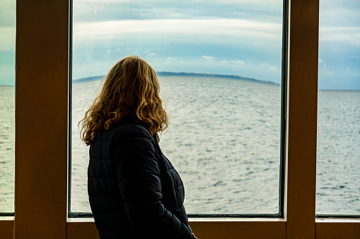 Helsingborg, Sweden A woman looks out a window of a ferry  whose view is distorted on a ferry to Denmark.