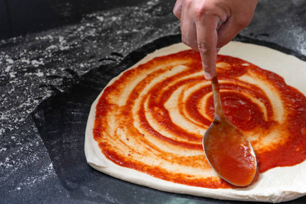 istock Pizzaiolo spreads tomato sauce onto pizza 1780166395