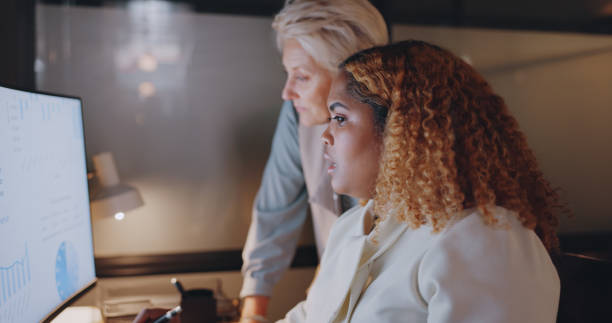 istock Business women, planning and computer work at night with collaboration and working together in office. Communication, conversation and teamwork with internet report at desk with manager and email 1780169249