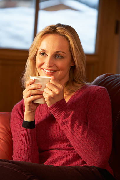 istock Middle Aged Woman Relaxing With Hot Drink On Sofa 178017192
