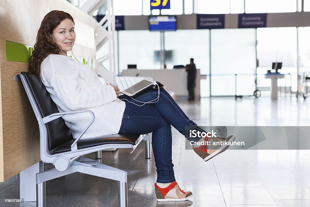 Mujer sonriente con dispositivos sala de estar en el Aeropuerto de estar - Foto de stock de Adulto libre de derechos