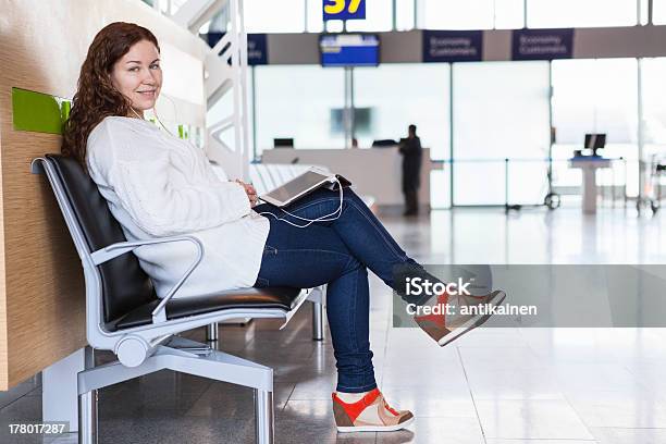 Mulher Sorridente Com Dispositivos Sentado Na Área De Embarque - Fotografias de stock e mais imagens de Adulto
