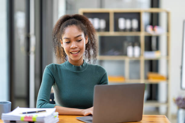 istock Smiling African American businesswoman sitting on a laptop thinking happily analyzing data 1780179675