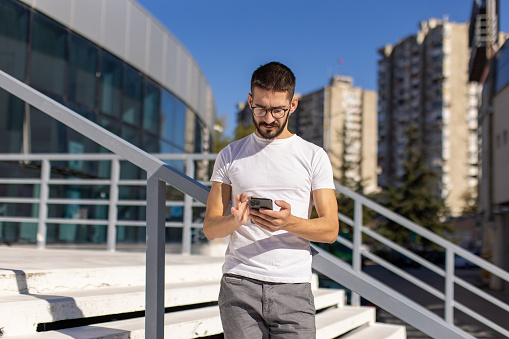 A mid adult Caucasian male protestor using a smartphone in an urban outdoor area