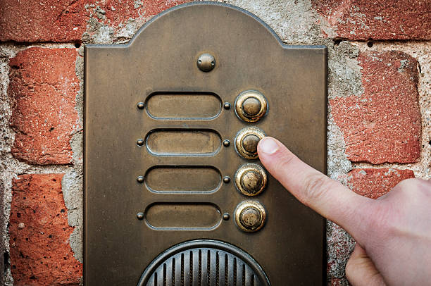 Finger ringing a door bell A visitor pushing a brass, antique doorbell mounted to a brick wall doorbell photos stock pictures, royalty-free photos & images