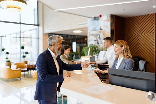 Modern man paying something with a credit card at the hotel reception