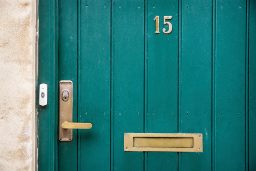 Frontal closeup shot of a green-painted wooden door with the number 15. 