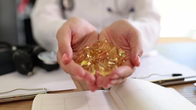Doctor holding many omega 3 capsules in hands in clinic closeup 4k movie slow motion