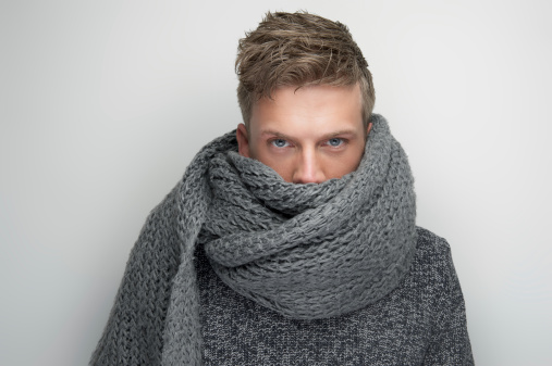 Portrait of a handsome man with face covered by gray wool scarf