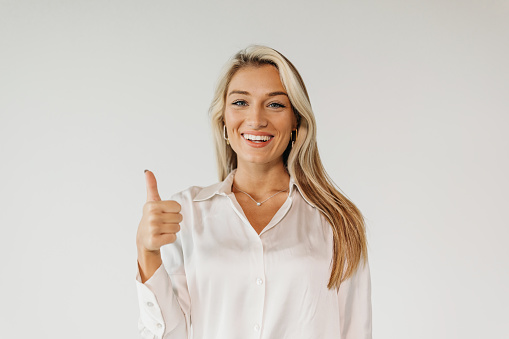 A cheerful young woman with a thumbs-up gesture, symbolizing joy and winning attitude.