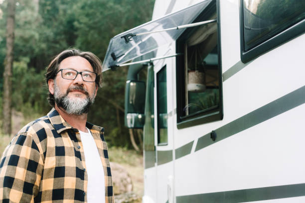 istock One man outside a camper van motorhome rv vehicle looking the outdoors in mountain forest woods scenic destination. Alternative travel and lifestyle people. Mature male with beard and camper van 1780249319